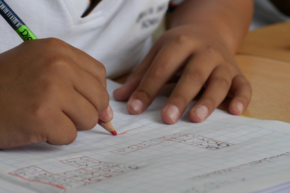 A kid hands writing with pencil on notebook