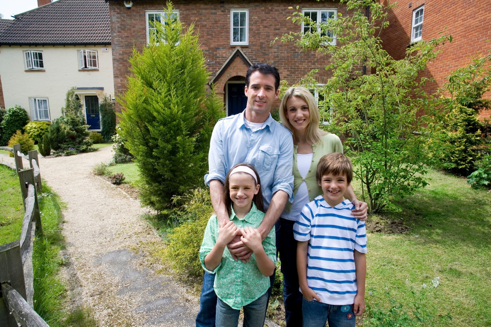 A nuclear family smiling in front of their newly-brought home